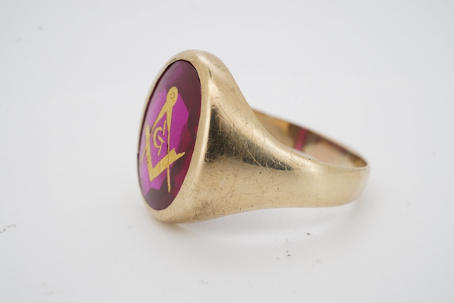 A 9ct and synthetic ruby set signet ring, the stone carved with gilded masonic symbol, size S/T, gross weight 5.8 grams. Condition - fair to good